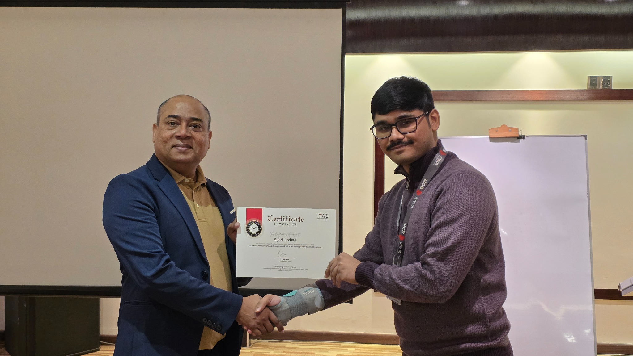 Zia Hasan presenting a workshop certificate to a participant
